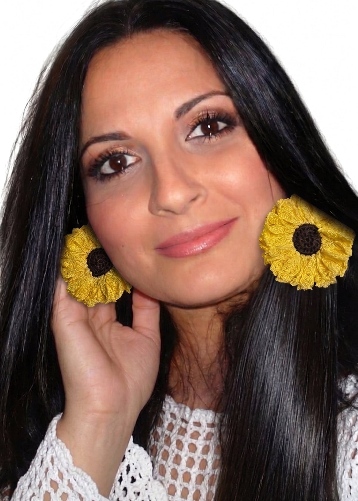 Modelo luciendo pendientes de crochet con forma de girasol amarillo y centro marrón.